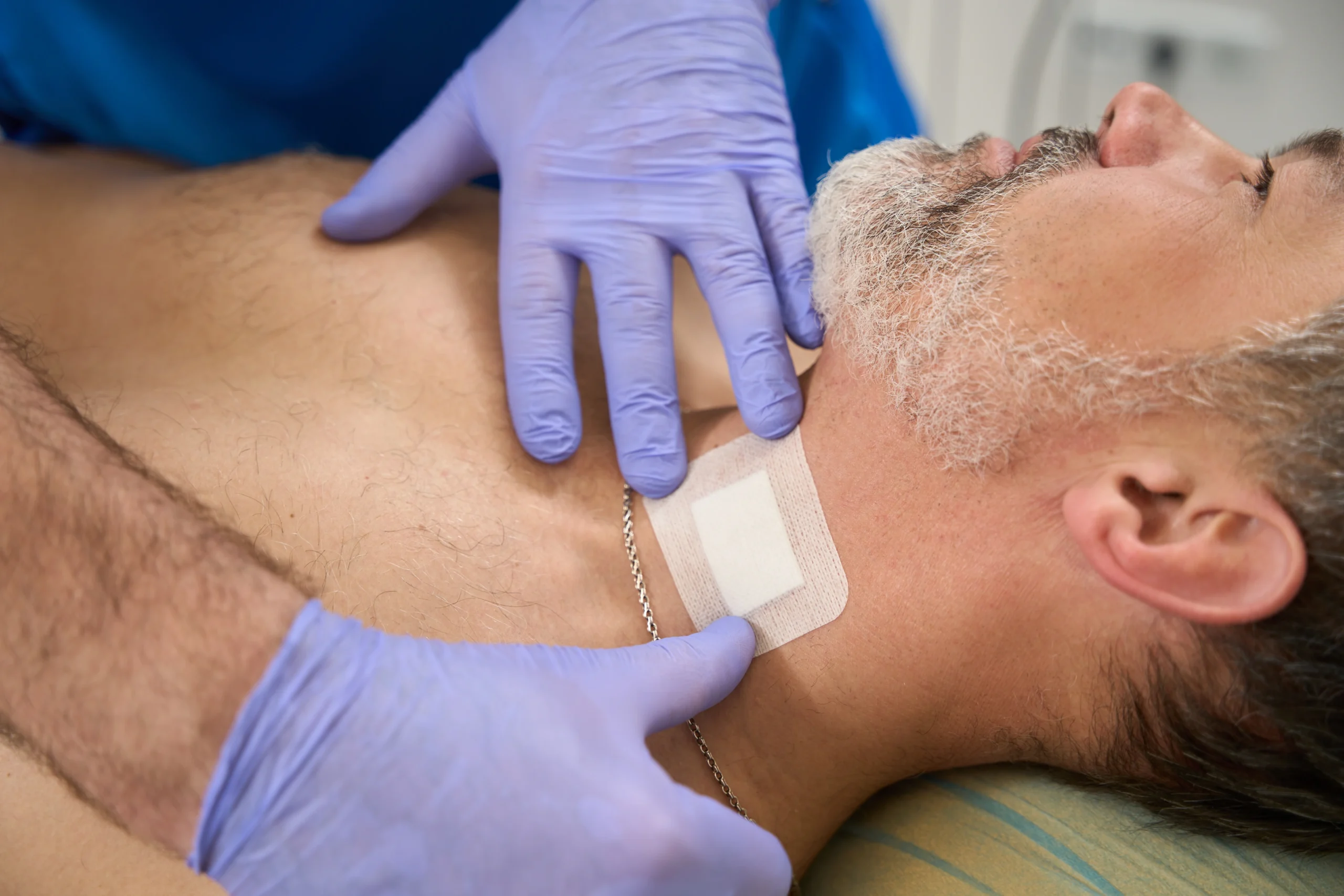 Tracheostomy-Home-Care-in-Minneapolis-MN-1 man on hospital bed has bandage placed on his neck