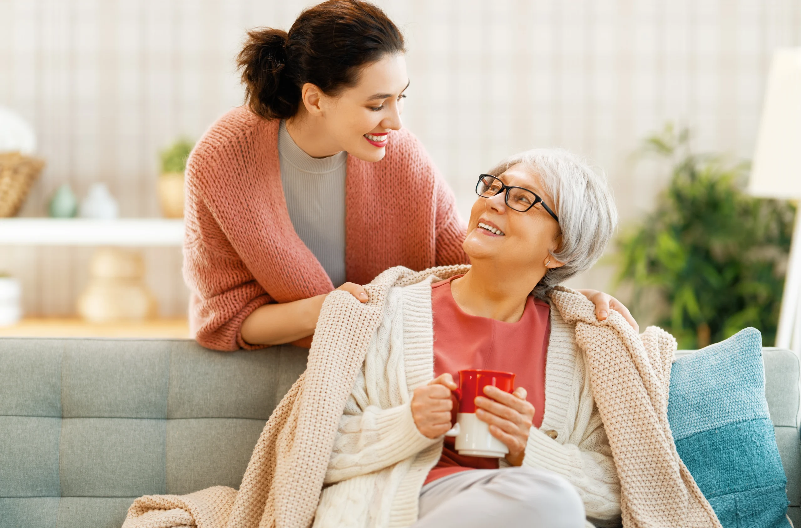 companion-home-care-in-Minneapolis-MN-2 smiling woman in pink sweater smiling with elderly woman on couch