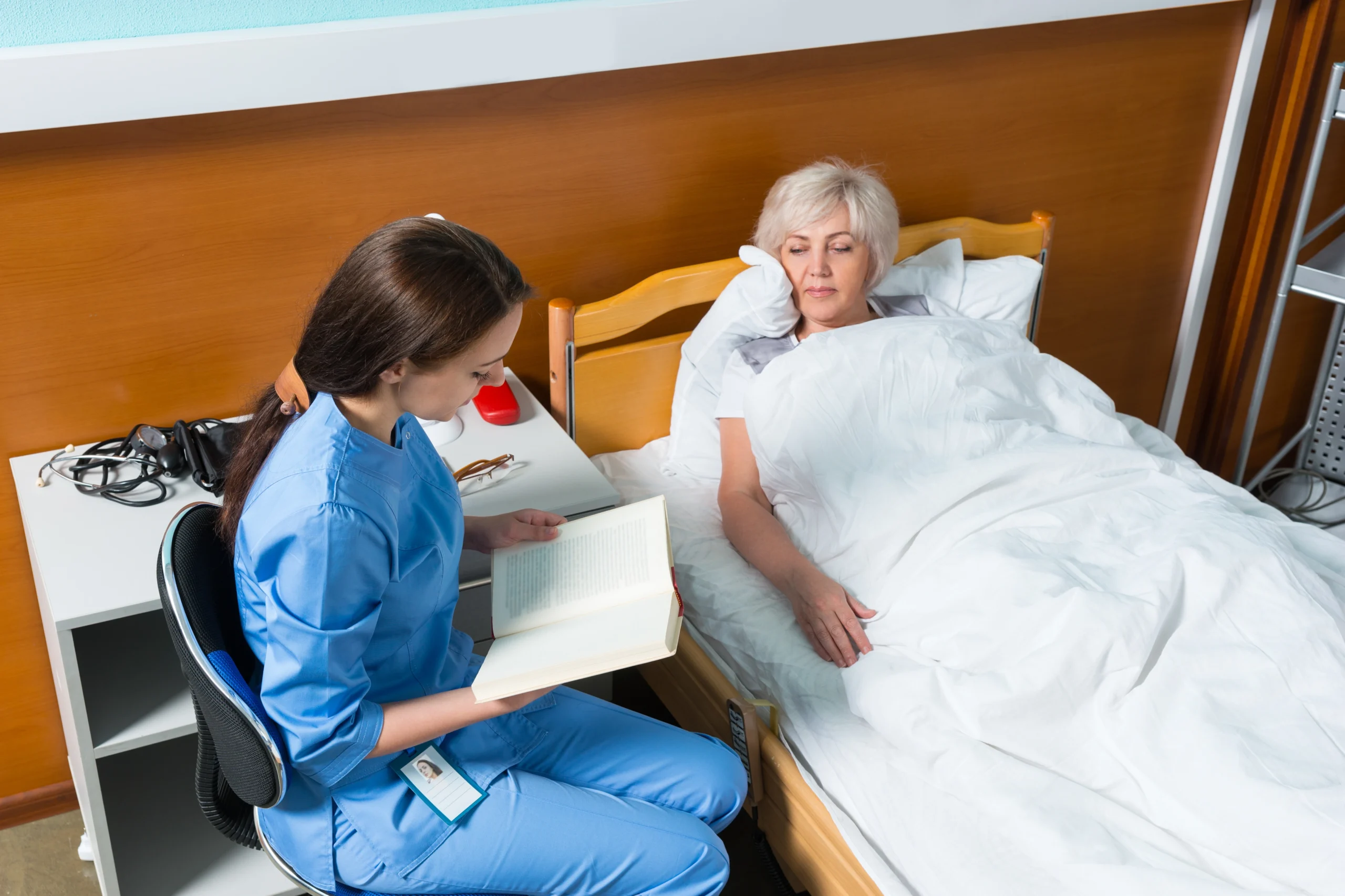 in-home-care-in-Minneapolis-MN-2 young nurse reading to elderly woman in bed